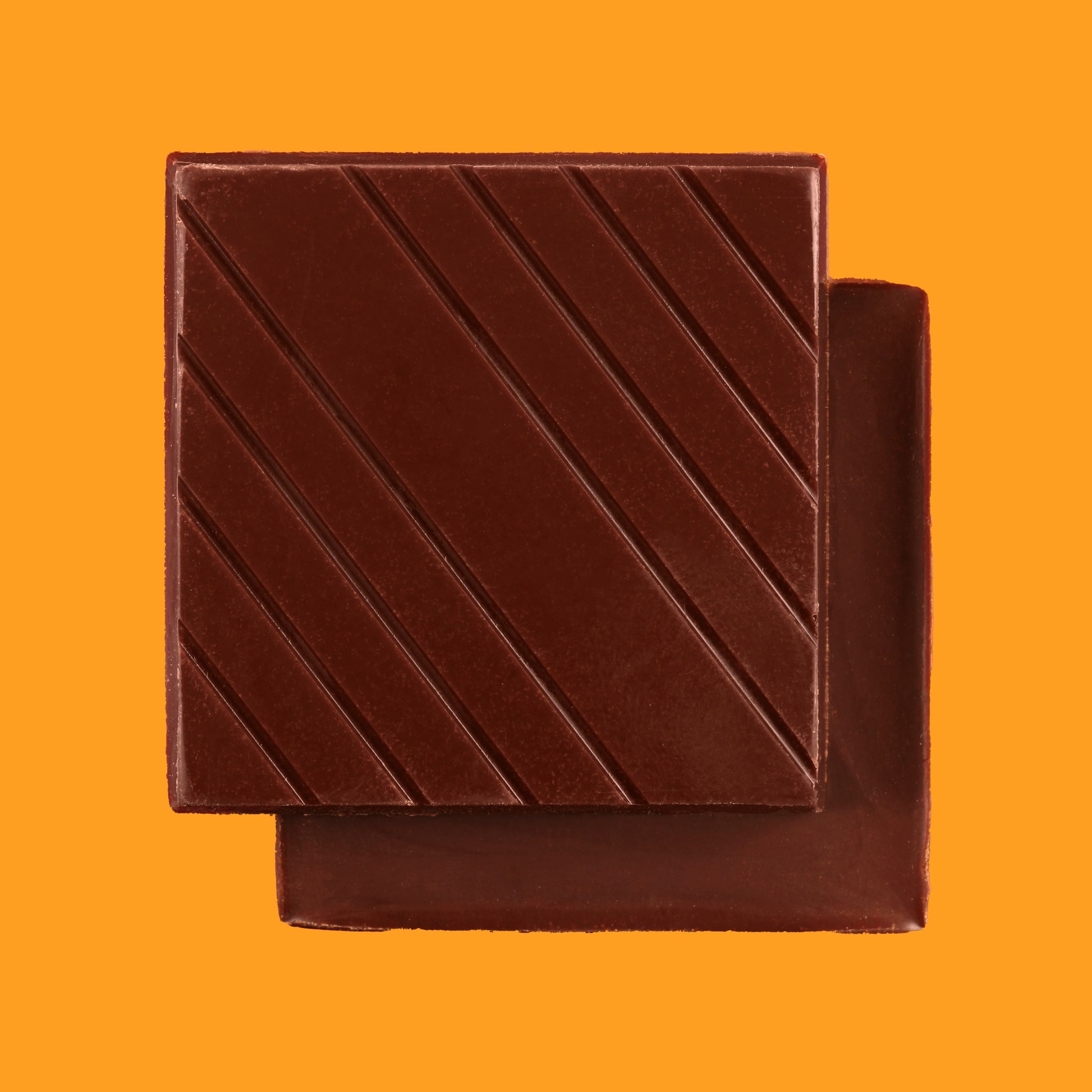 Stack of dark chocolate bars using cocoa beans from Tsiriari, Peru on an orange background