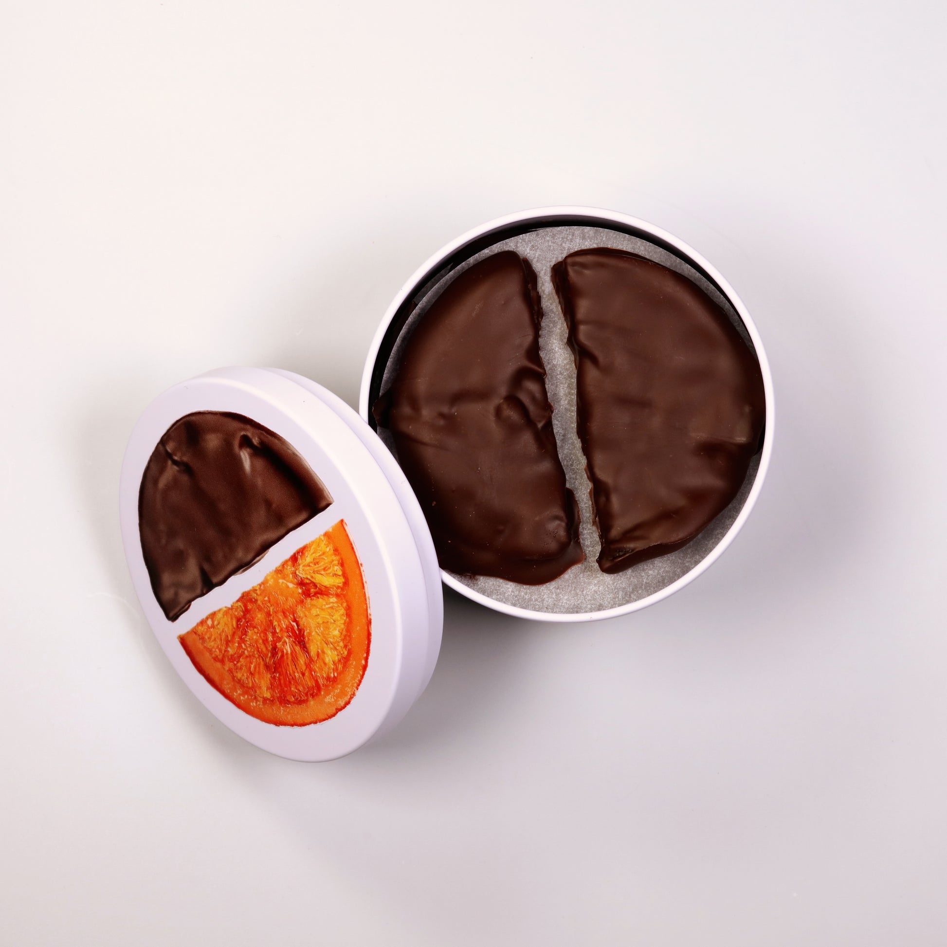 Two chocolate-covered treats in white and black containers on a light gray background