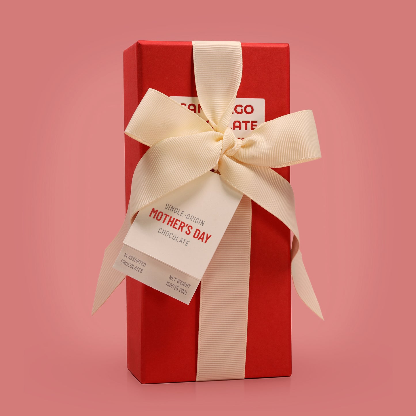 Red gift box with a cream ribbon and 'Mother's Day' tag on a pink background
