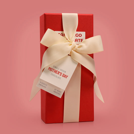 Red gift box with a cream ribbon and 'Mother's Day' tag on a pink background