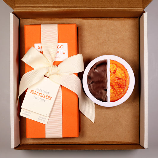 Gift box with an orange and white striped design, a white bow, and a half-chocolate, half-plain cookie in a small white bowl.