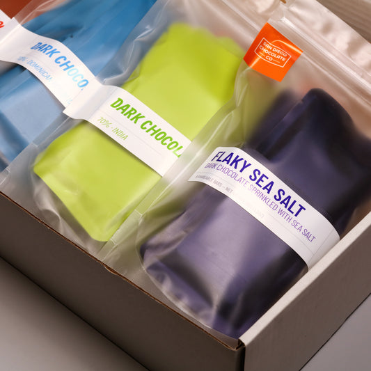 Three chocolate bars in clear packaging with visible branding on a neutral background
